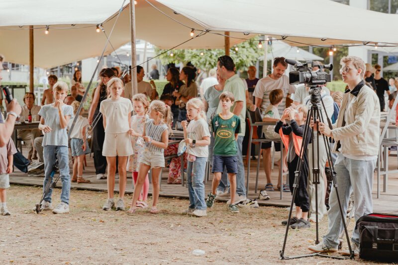 Ouders en kinderen bij een lokaal evenement onder de tenten op het landgoed.