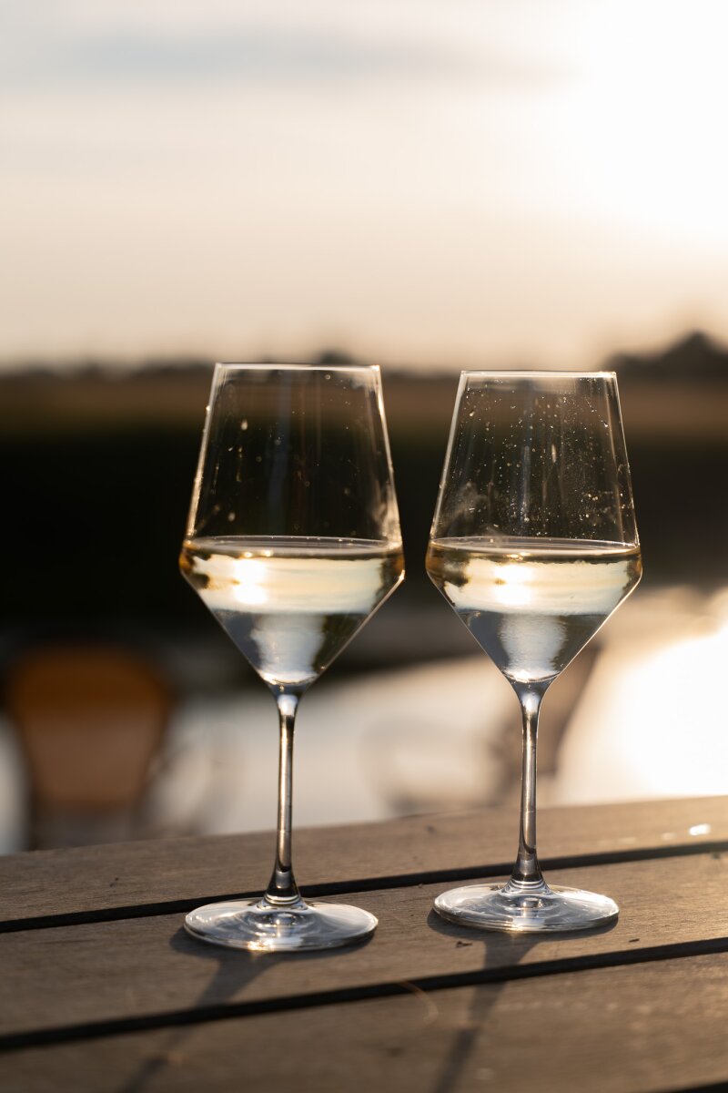 Twee glazen witte wijn op het terras bij zonsondergang.