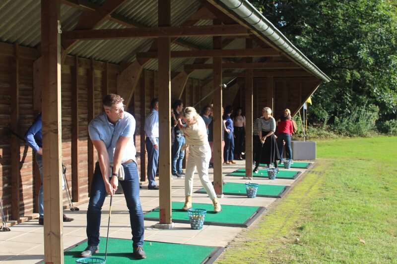 Deelnemer oefent een golfswing tijdens een golfclinic op het landgoed.